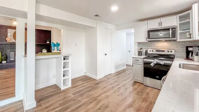 a kitchen with stainless steel appliances a stove top oven a sink dishwasher and a refrigerator