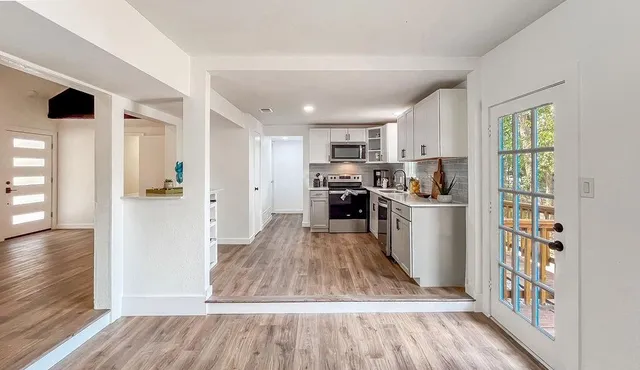 a kitchen with stainless steel appliances granite countertop a refrigerator a stove top oven a sink and dishwasher with wooden floor