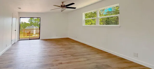 an empty room with wooden floor and windows