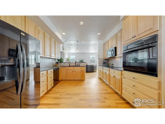 a kitchen with stainless steel appliances kitchen island granite countertop a stove top oven a refrigerator a sink and dishwasher with white cabinets