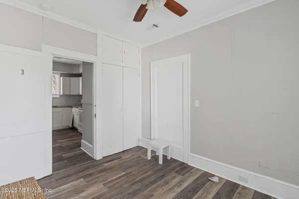 an empty room with wooden floor and ceiling fan