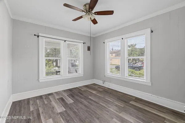 a view of an empty room with a window and wooden floor