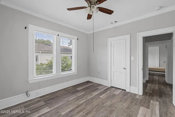 a view of an empty room with wooden floor and a window