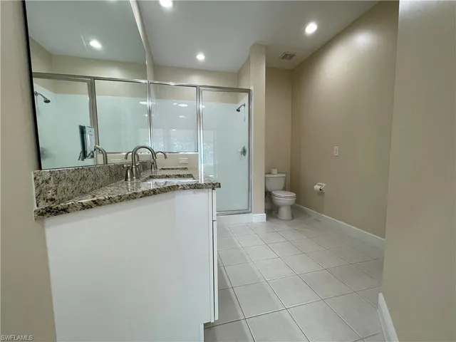 a bathroom with a granite countertop sink a toilet and a mirror