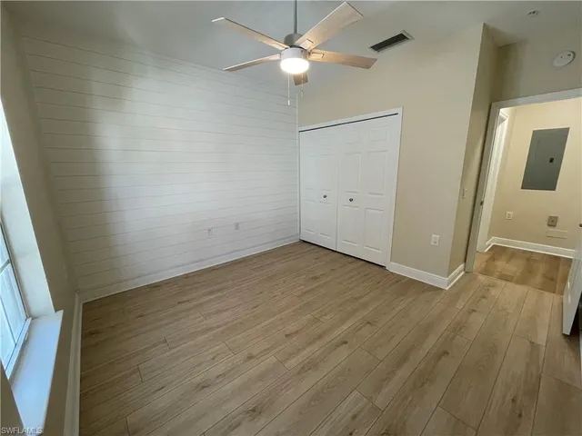 an empty room with wooden floor and fan