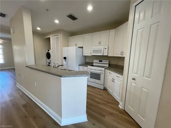 a kitchen with stainless steel appliances white cabinets a sink and wooden floor