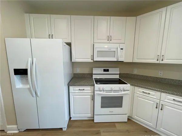 a kitchen with white cabinets and white appliances