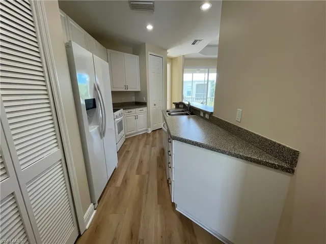 a kitchen with sink a refrigerator and wooden floor