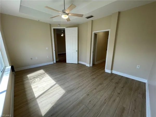 a view of empty room with wooden floor and fan