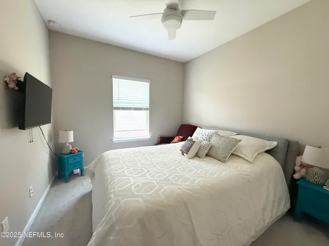 a bedroom with a bed and a flat tv screen on dresser