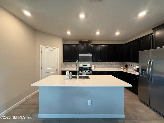 a large kitchen with stainless steel appliances a large counter top