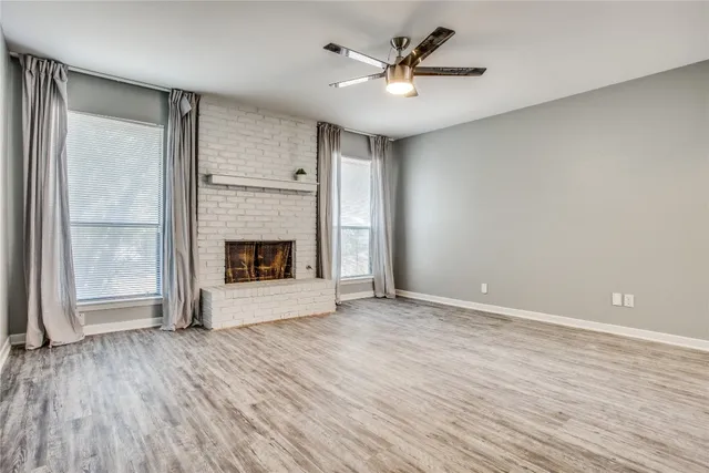 an empty room with wooden floor a ceiling fan and windows