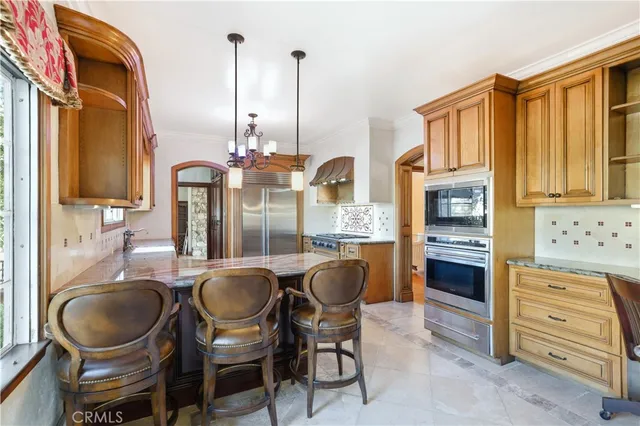 a large kitchen with a large counter top a sink stainless steel appliances and cabinets