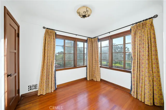 a view of an empty room with wooden floor and windows