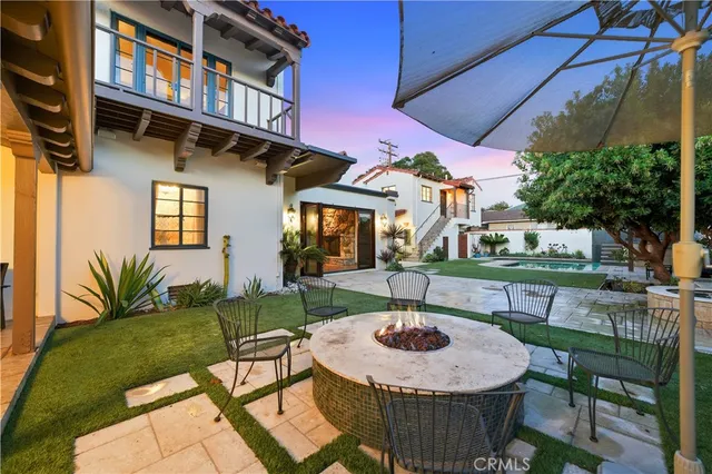 a view of a patio with couches table and chairs under an umbrella with a yard