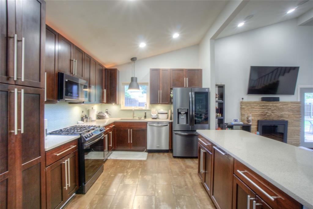 12231 Veronica Road Farmers Branch, TX 75234 - Photo 9 of 26 Modern kitchen featuring wood-finish flooring, dark wood cabinetry, stainless steel appliances, a light-toned countertop, and recessed lighting