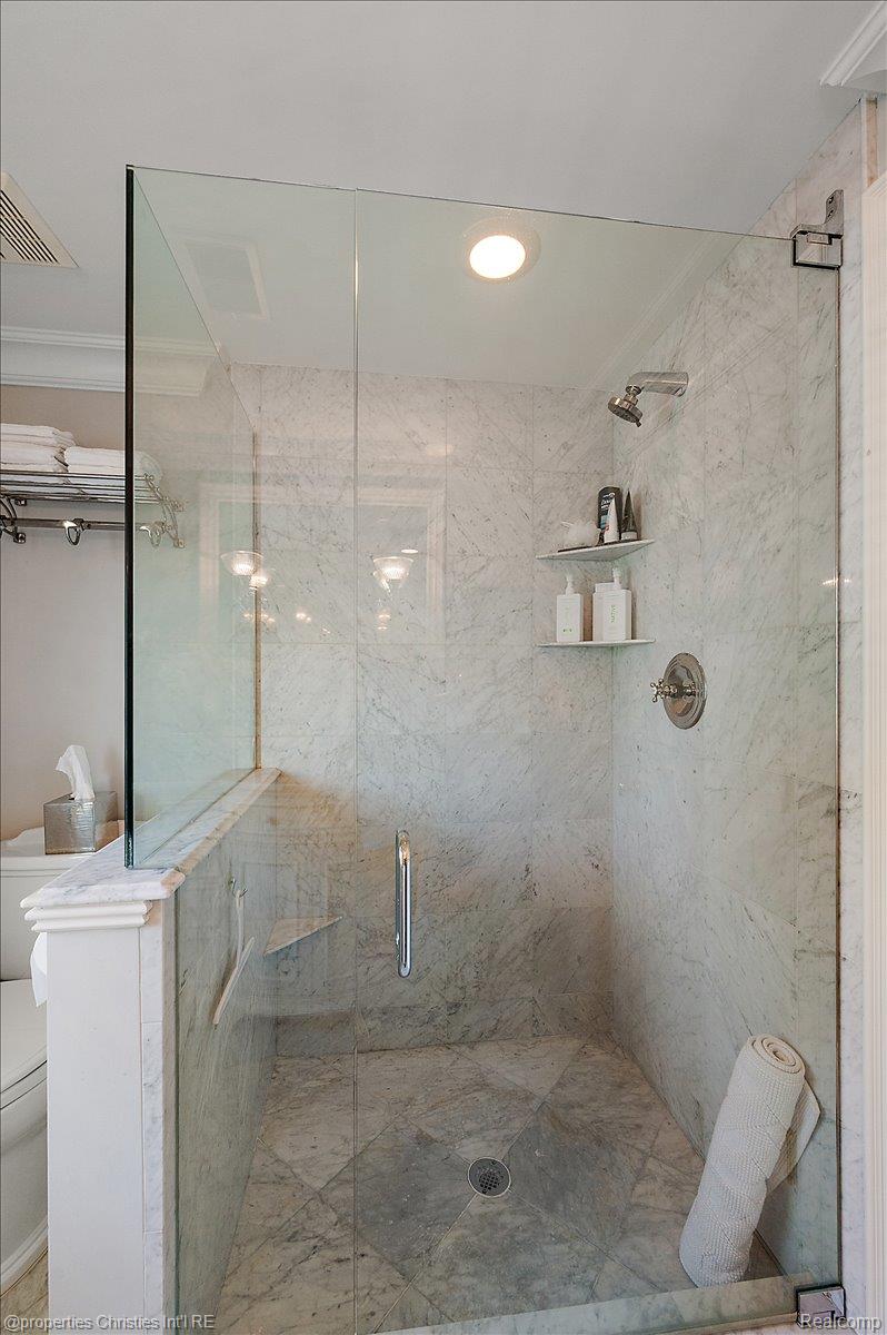 135 Clifton Road Bloomfield Hills, MI 48301 - Photo 55 of 77 Enclosed shower featuring full-height stone-finish walls, a glass enclosure, built-in shelving, a recessed light, and a chrome showerhead