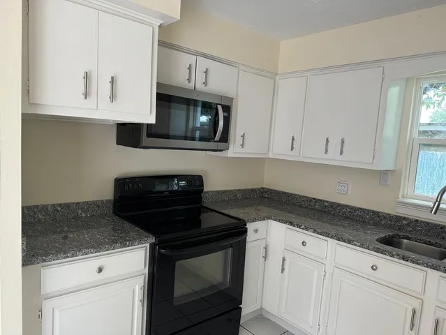 a kitchen with granite countertop white cabinets stainless steel appliances and a sink