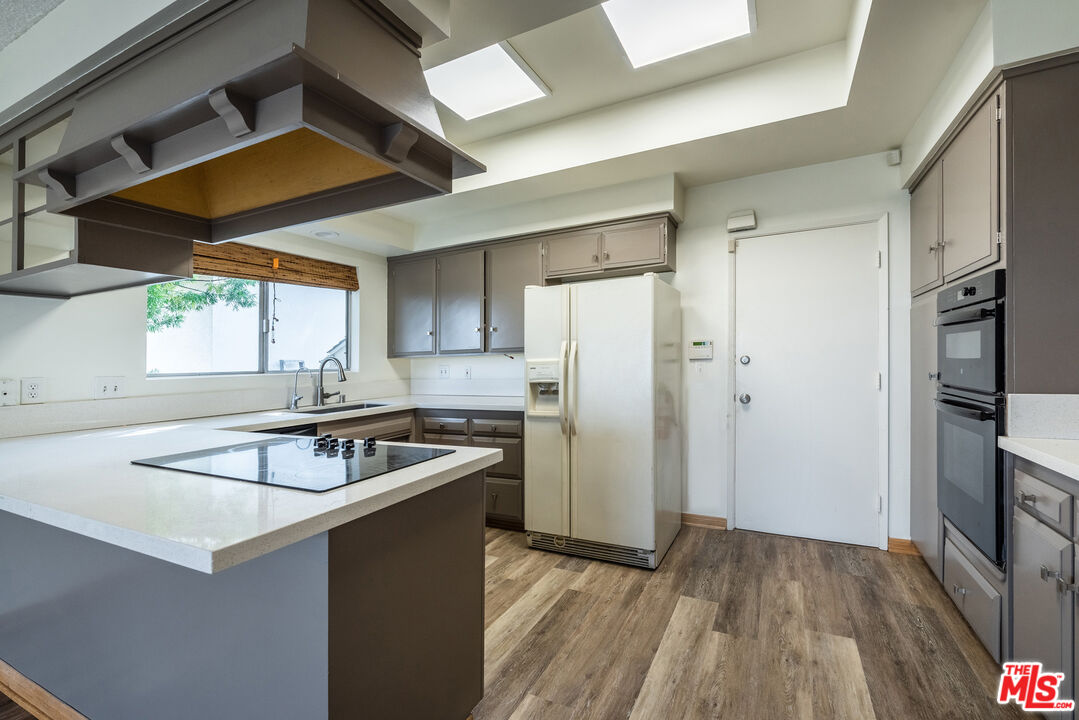 1342 Stradella Road Los Angeles, CA 90077 - Photo 7 of 24 a kitchen that has a sink a refrigerator and cabinets