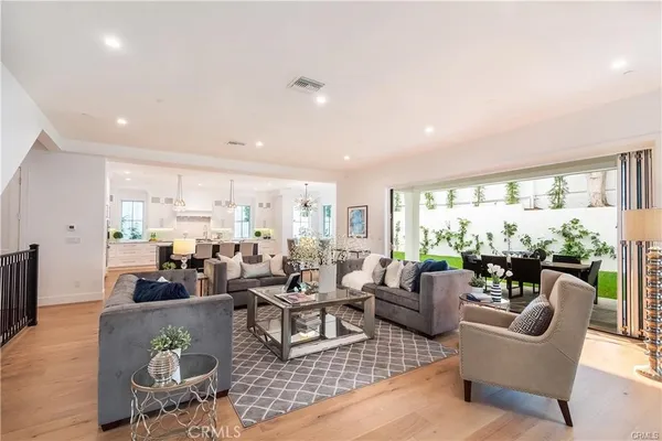 a living room with furniture large windows and wooden floor