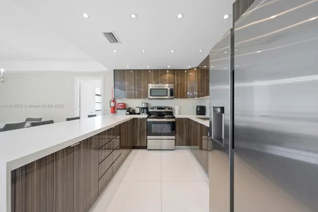 a kitchen with stainless steel appliances granite countertop a refrigerator a sink a stove top oven a sink and dishwasher