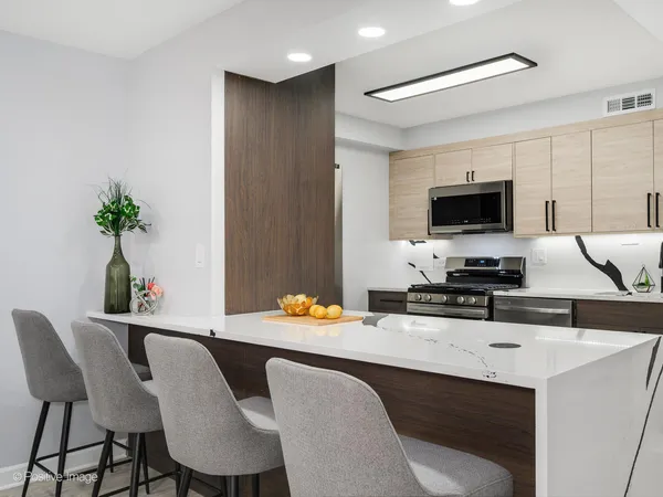 a dining room with furniture a potted plant and a kitchen view