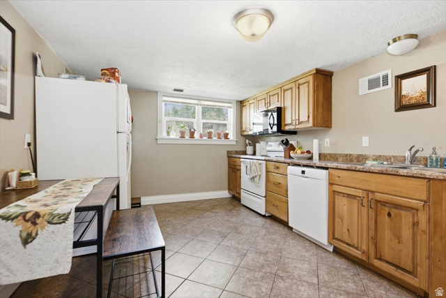 565 East 800 North Logan, UT 84321 - Photo 24 of 27 Kitchen featuring wood-finish cabinetry, tile flooring, and a double window