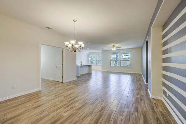 a view of an empty room with window and wooden floor