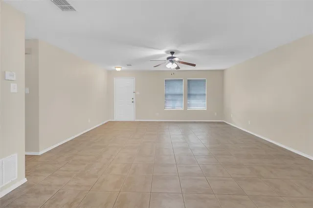 a view of an empty room with a chandelier fan