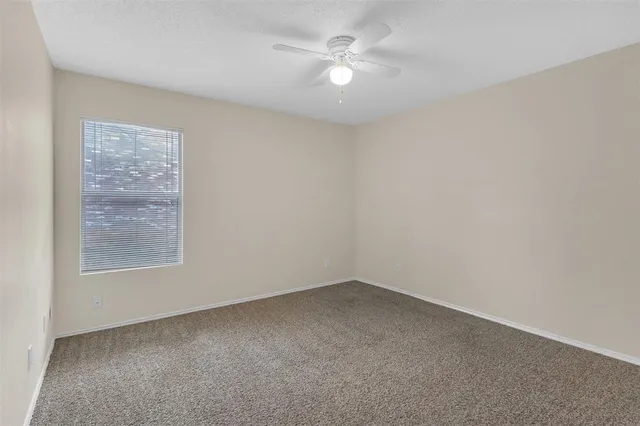 an empty room with a window and a fan