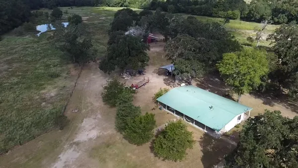 an aerial view of a residential houses with outdoor space and trees