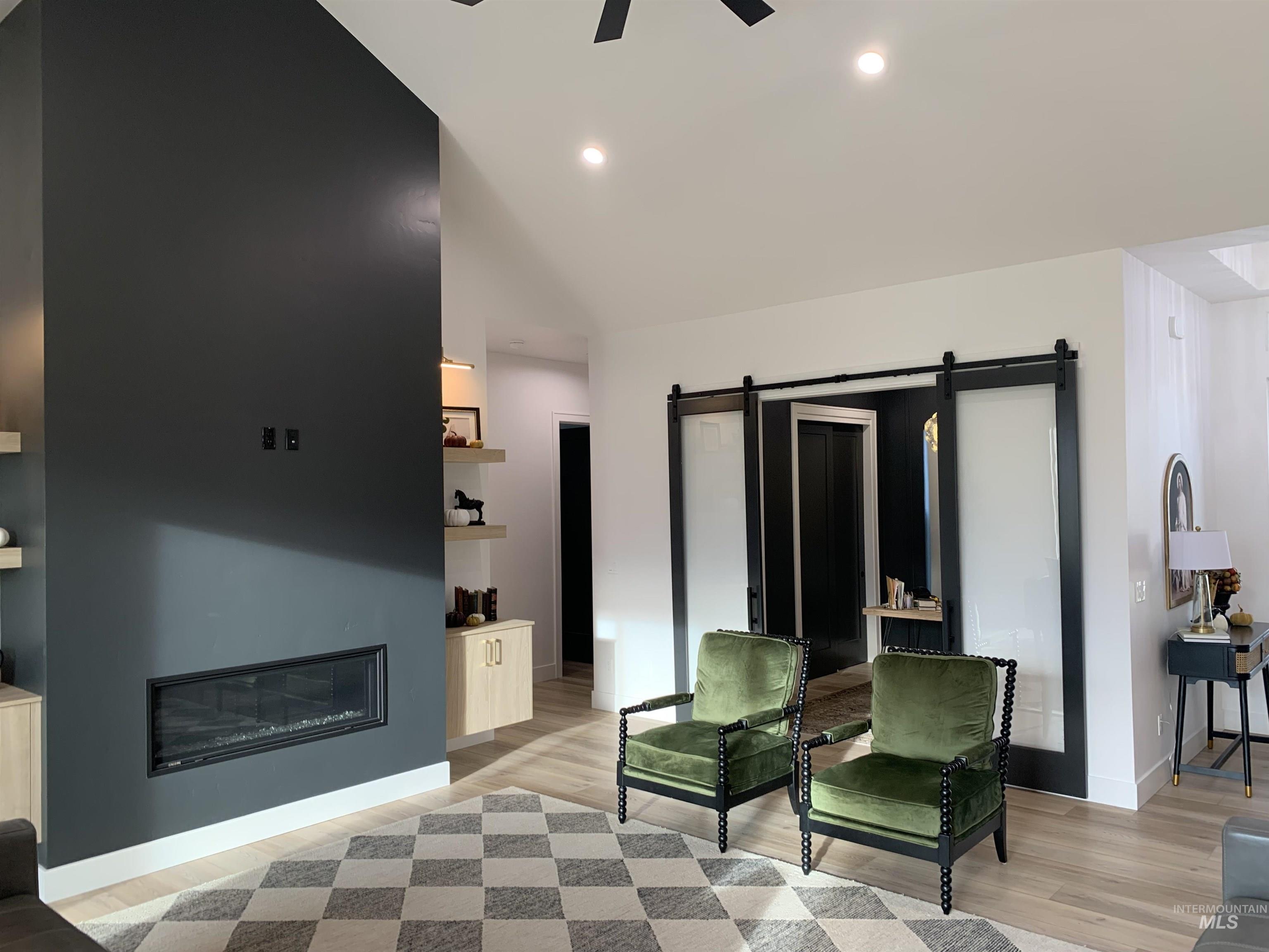 24501 Himark Way Caldwell, ID 83607 - Photo 21 of 27 Bedroom with a barn door, a glass covered fireplace, ceiling fan, light wood-style floors, and recessed lighting