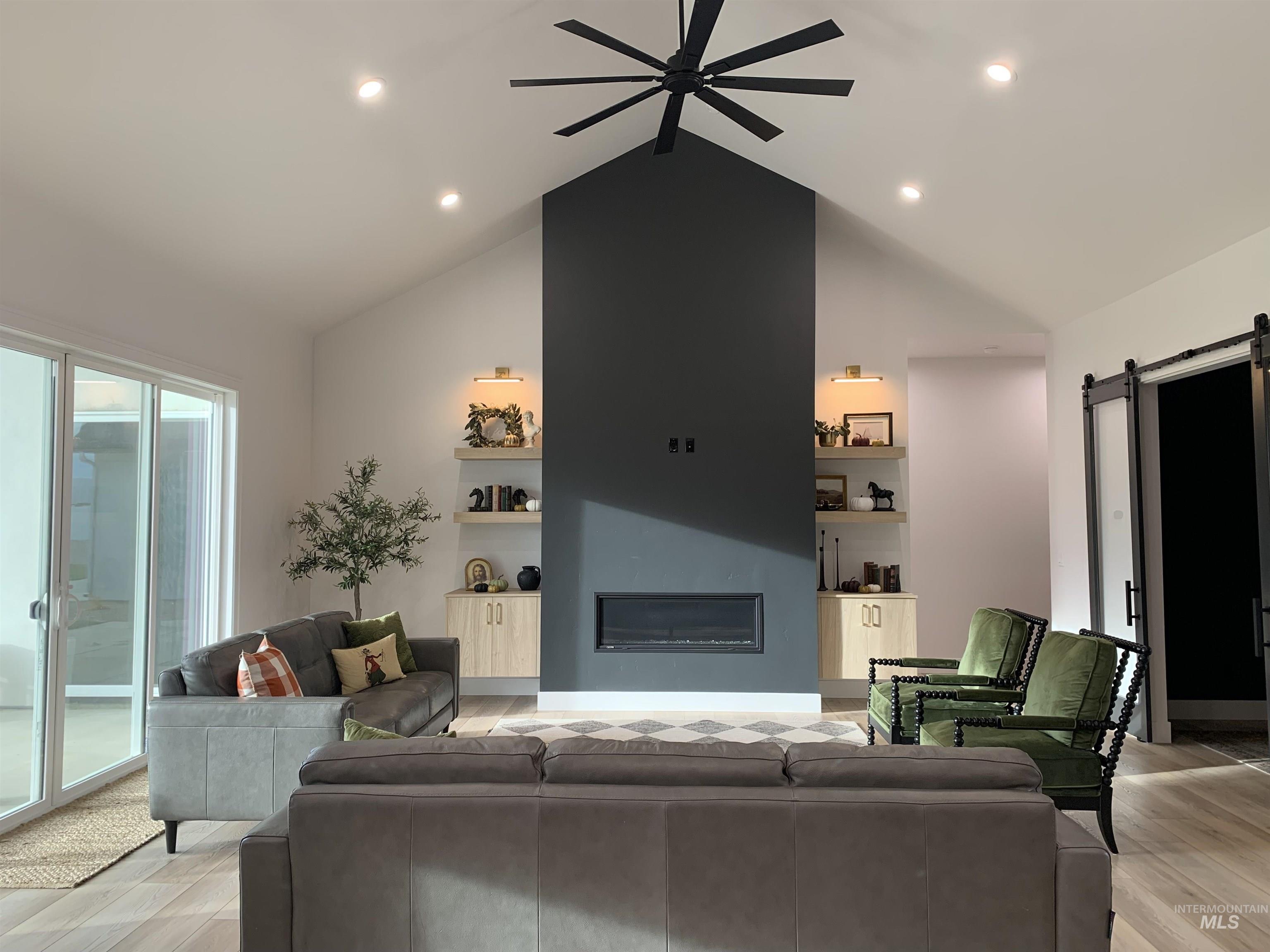 24501 Himark Way Caldwell, ID 83607 - Photo 4 of 27 Living area featuring a barn door, a glass covered fireplace, a ceiling fan, built in features, and recessed lighting