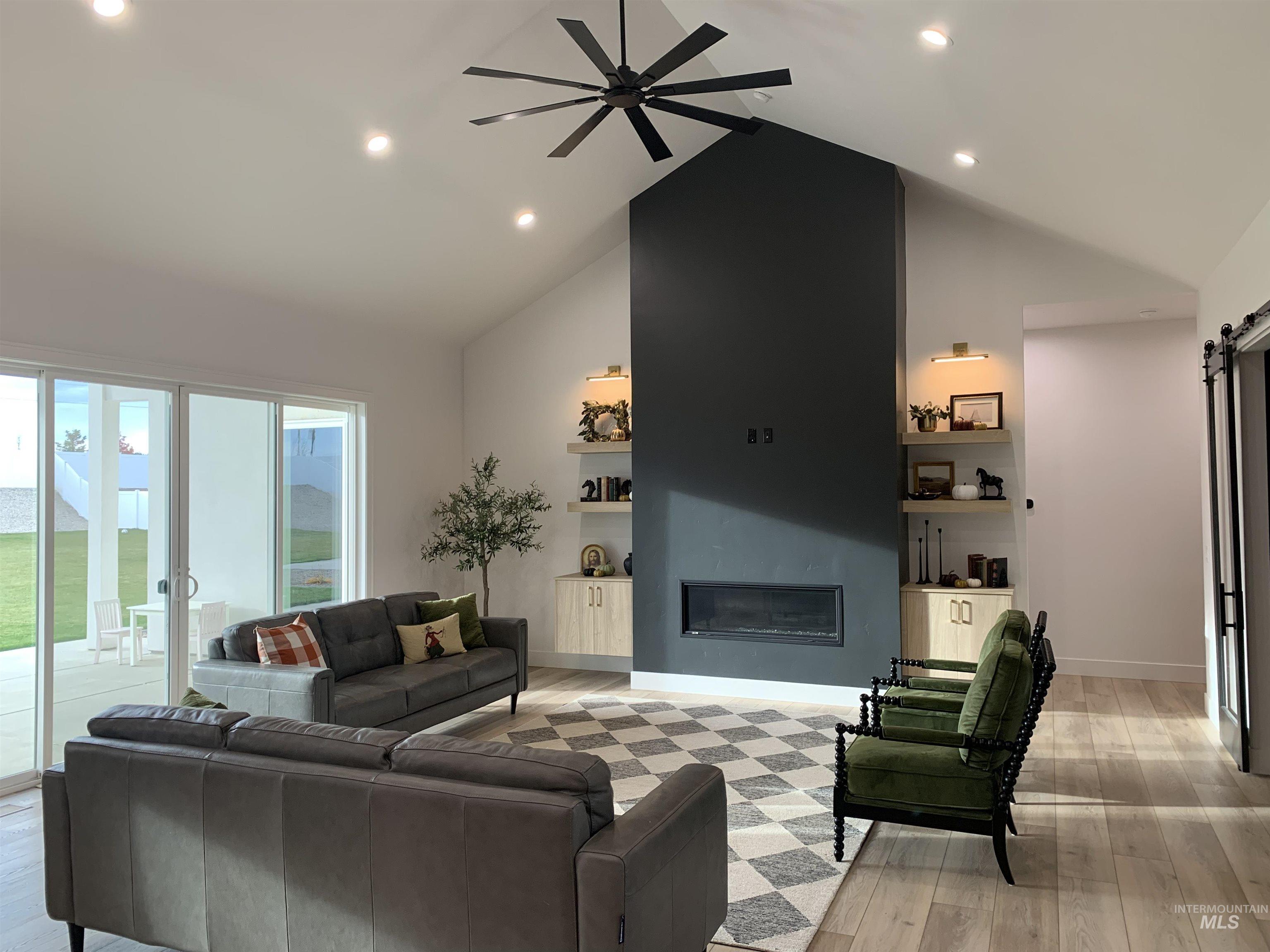 24501 Himark Way Caldwell, ID 83607 - Photo 5 of 27 Living area featuring a barn door, recessed lighting, a glass covered fireplace, high vaulted ceiling, and built in features
