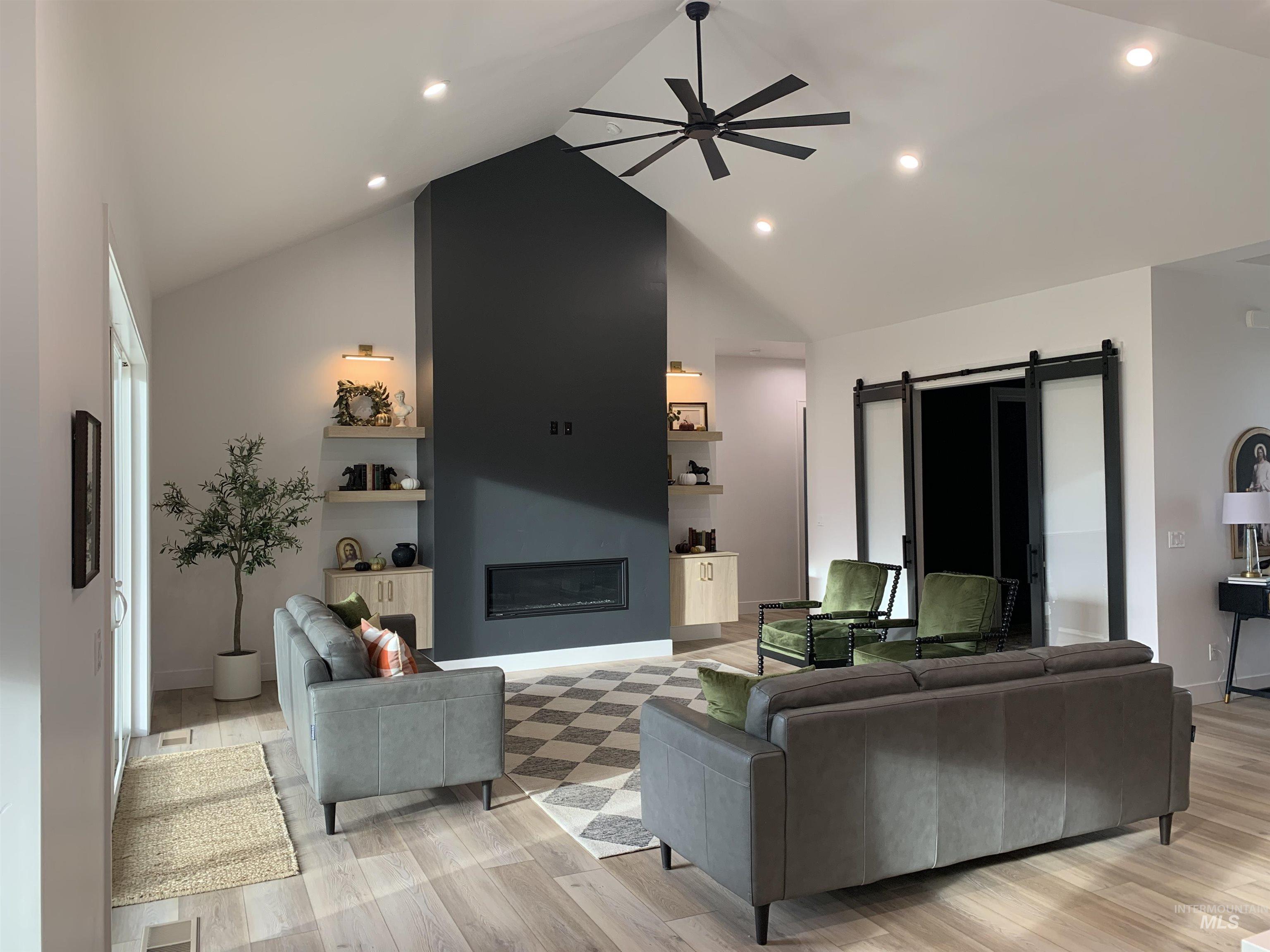 24501 Himark Way Caldwell, ID 83607 - Photo 6 of 27 Living area featuring a barn door, a glass covered fireplace, built in features, high vaulted ceiling, and recessed lighting