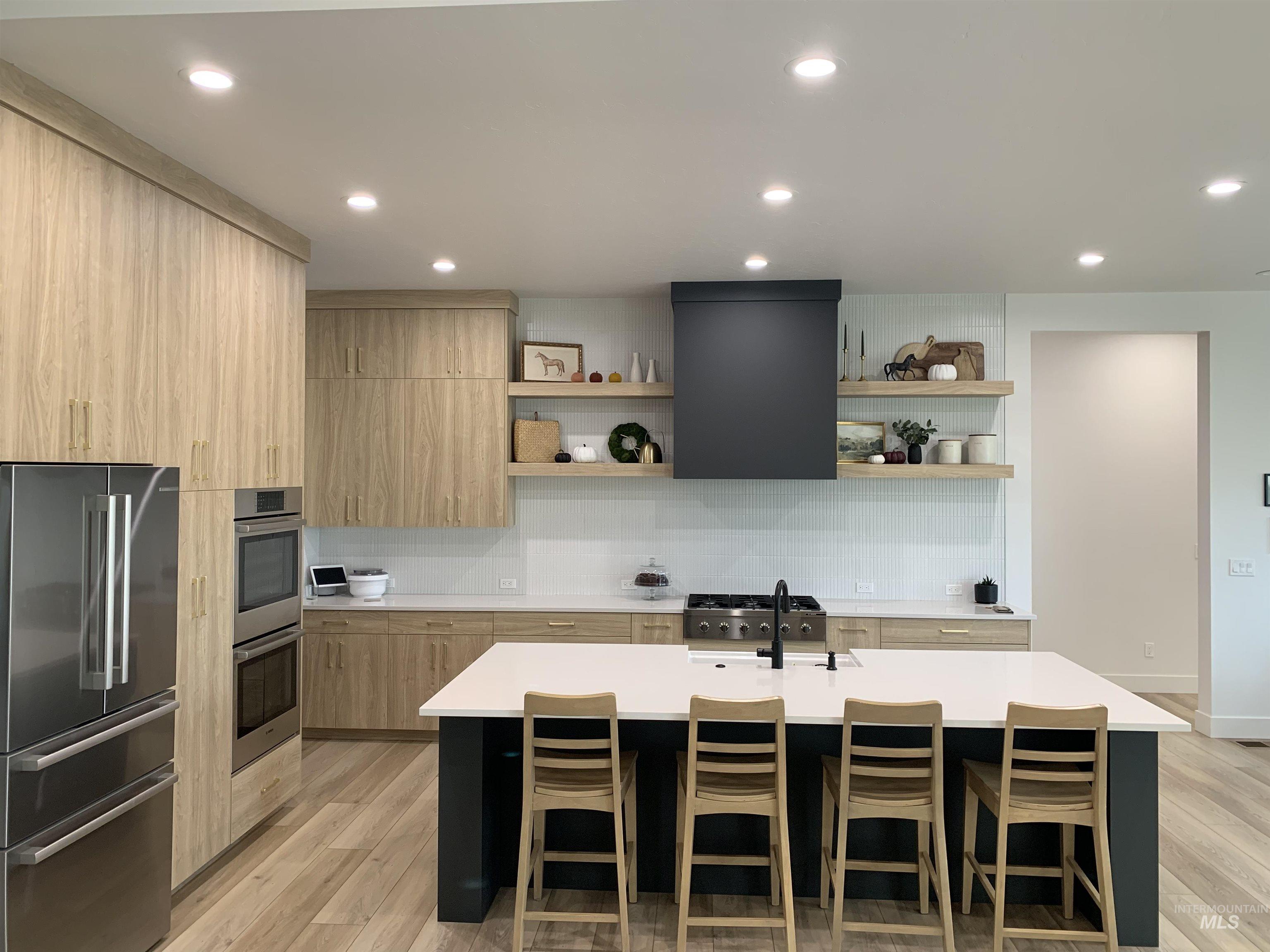 24501 Himark Way Caldwell, ID 83607 - Photo 8 of 27 Kitchen with backsplash, appliances with stainless steel finishes, modern cabinets, a kitchen breakfast bar, and light brown cabinetry