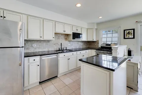 a kitchen with granite countertop white cabinets white stainless steel appliances and a sink