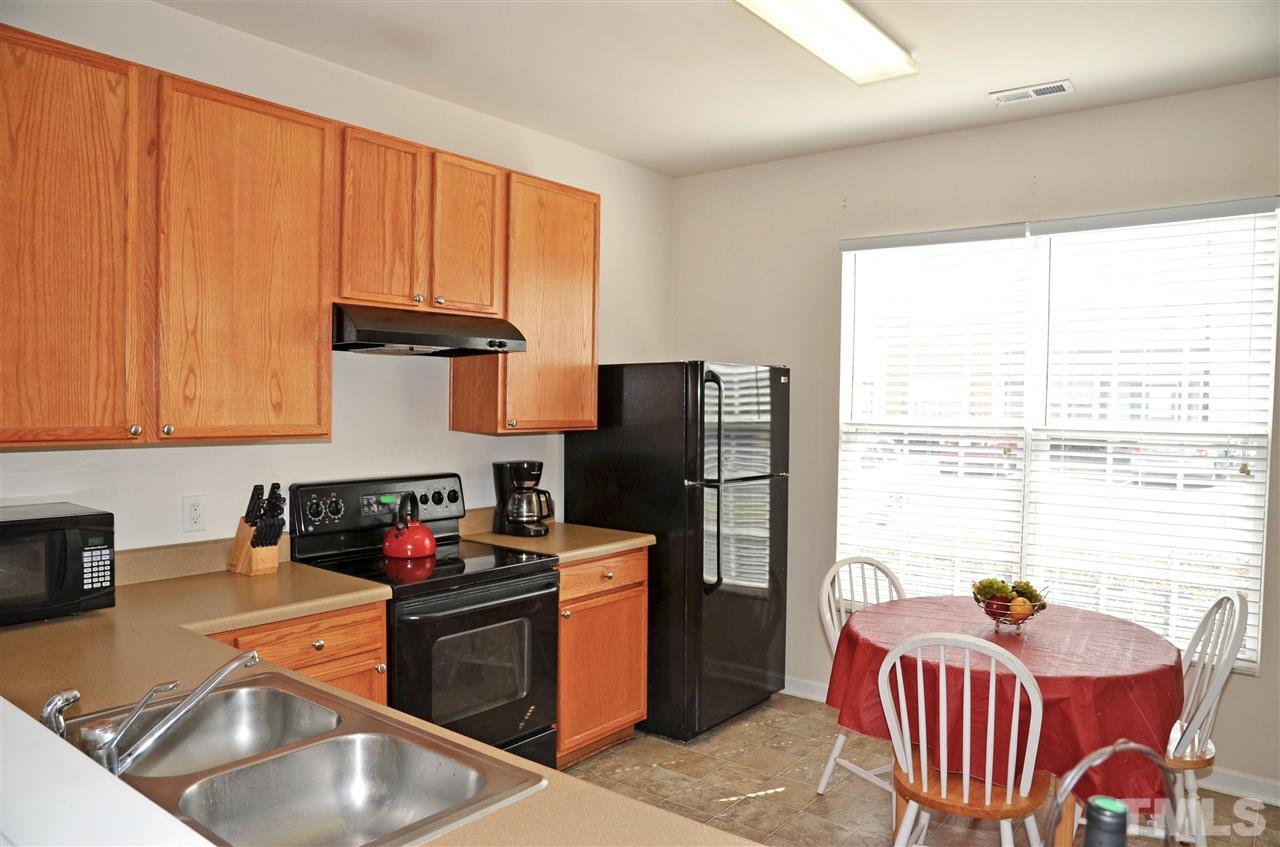 8520 Silhouette Place Raleigh, NC 27613 - Photo 7 of 17 a kitchen with stainless steel appliances granite countertop a refrigerator a sink dishwasher a stove and a dining table with wooden cabinet
