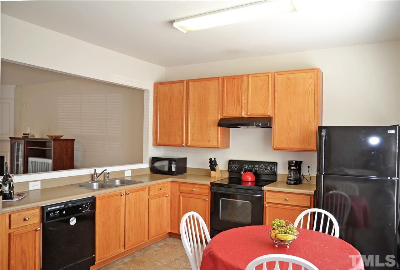 8520 Silhouette Place Raleigh, NC 27613 - Photo 8 of 17 a kitchen with stainless steel appliances granite countertop a stove top oven a sink dishwasher and a dining table with wooden cabinet