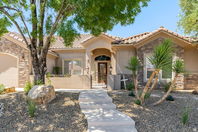 1609 East 10 S Street St. George, UT 84790 - Photo 5 of 68 Front exterior featuring a stucco and stone facade, concrete tile roof, and a wood entry door with an arched transom