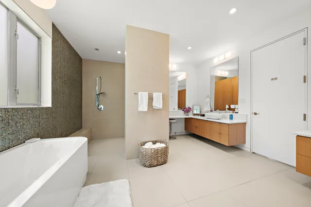 a bathroom with a tub a double vanity sink and mirror