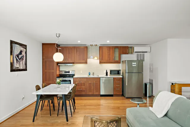 a open kitchen with stainless steel appliances kitchen island granite countertop a refrigerator a stove top oven and a dining table with wooden floor