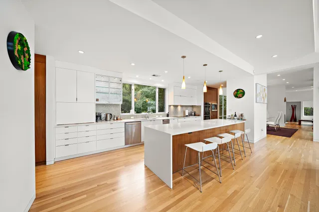 a large white kitchen with wooden floors and stainless steel appliances