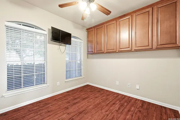 a view of empty room with wooden floor and fan