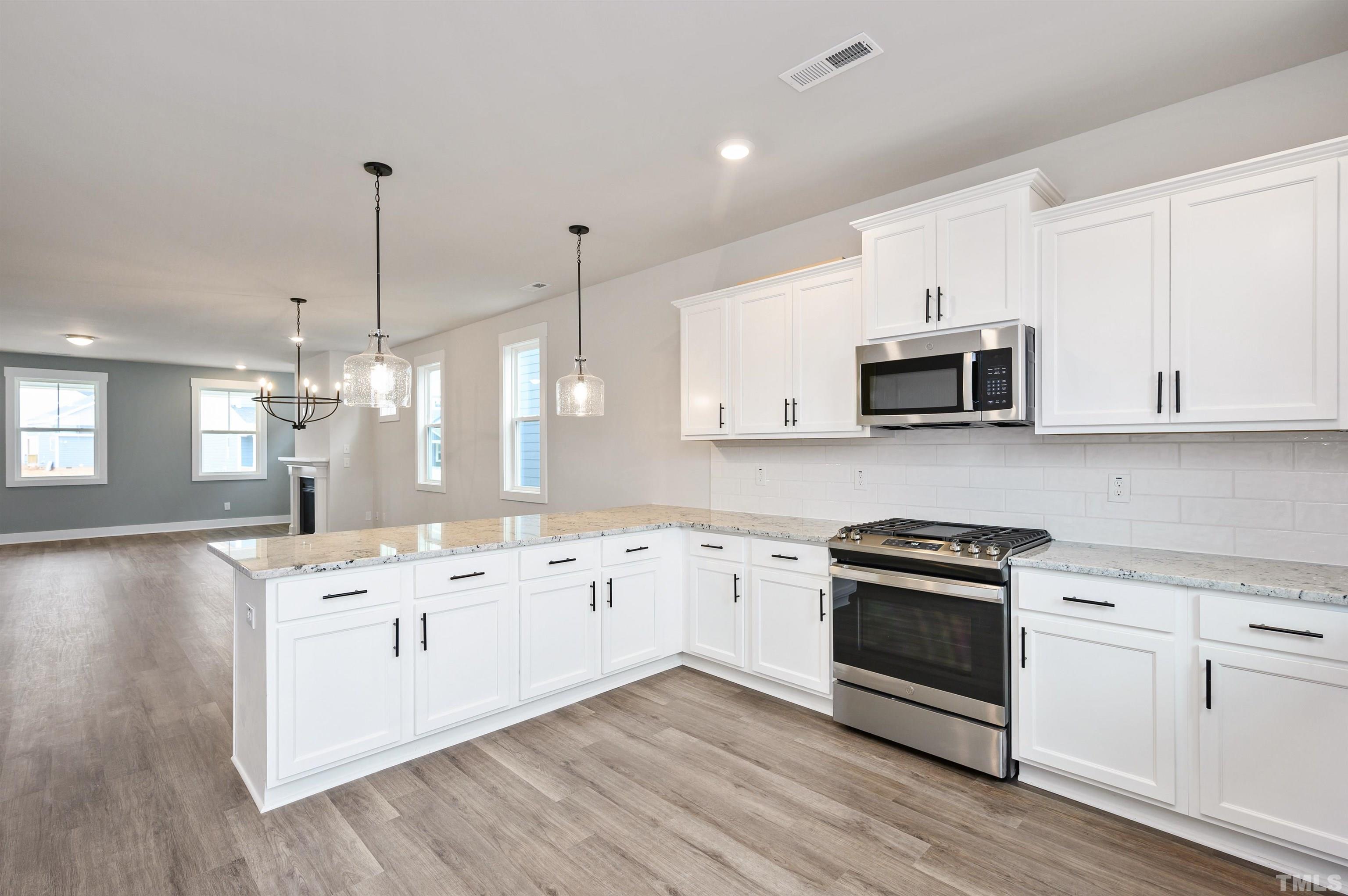 517 Friendship Chapel Road, Unit HVA0055 Wake Forest, NC 27587 - Photo 38 of 58 a kitchen with stainless steel appliances granite countertop a sink stove and white cabinets with wooden floor
