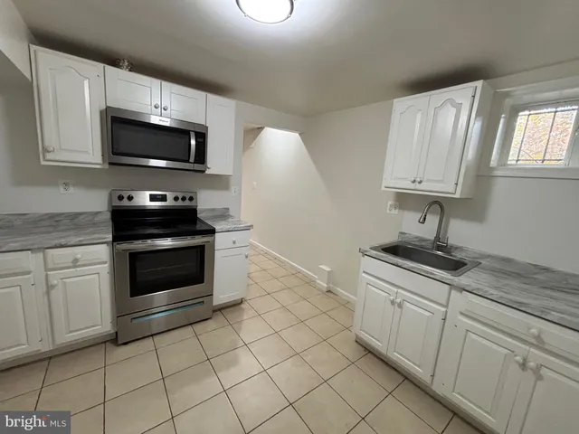 a kitchen with granite countertop white cabinets stainless steel appliances and a sink