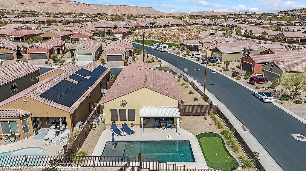 1304 Cottage Ridge Mesquite, NV 89034 - Photo 42 of 52 An aerial perspective reveals a charming desert home with solar panels, private pool, and putting green.