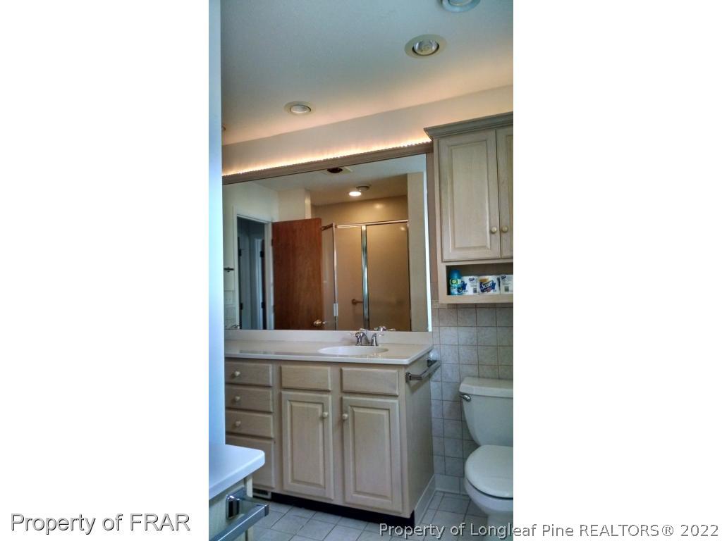 166 Boiling Spring Circle Southern Pines, NC 28387 - Photo 5 of 19 a bathroom with a sink a toilet a mirror and vanity