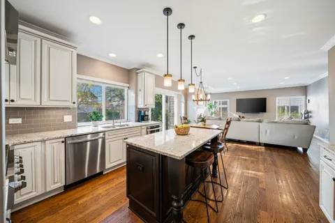 a kitchen with stainless steel appliances granite countertop wooden floor sink stove and white cabinets with wooden floor