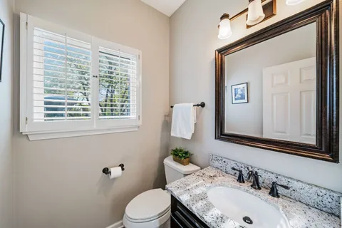a bathroom with a granite countertop sink vanity mirror and toilet